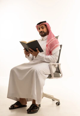 رجل سعودي بالثوب التقليدي يقرأ كتابا