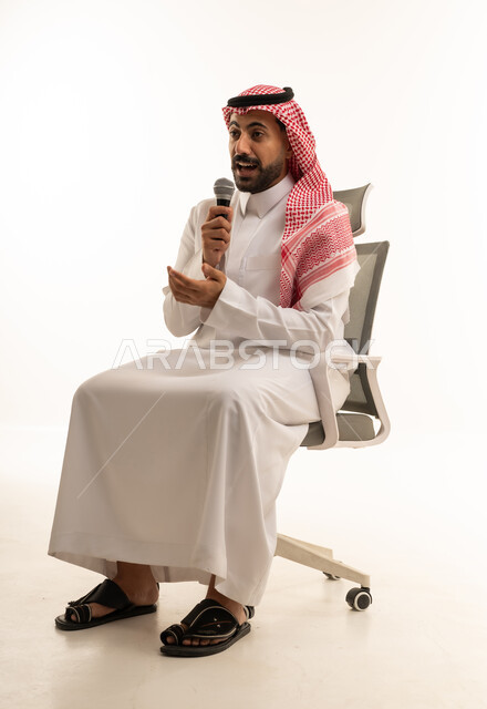رجل سعودي يتحدث في ميكروفون على كرسي مكتب