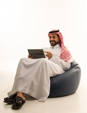 رجل سعودي يستخدم جهاز لوحي على مقعد استرخاء