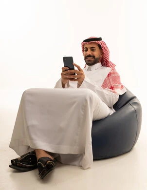 رجل سعودي يستخدم الهاتف الذكي على مقعد استرخاء