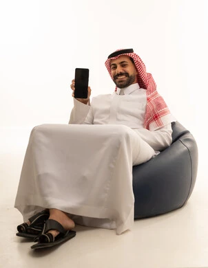 رجل سعودي بالثوب يحمل هاتفاً ذكياً في الاستوديو