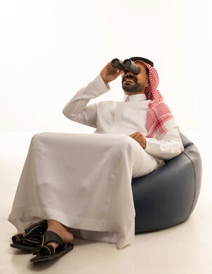 رجل سعودي بالثوب التقليدي يستخدم المنظار