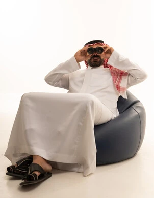 رجل سعودي بالثوب التقليدي يستخدم المنظار بخلفية بيضاء