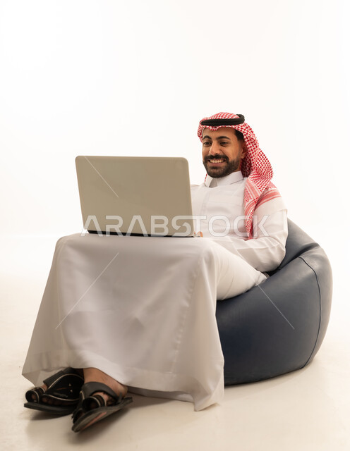 رجل سعودي يستخدم اللابتوب على كرسي بين باج