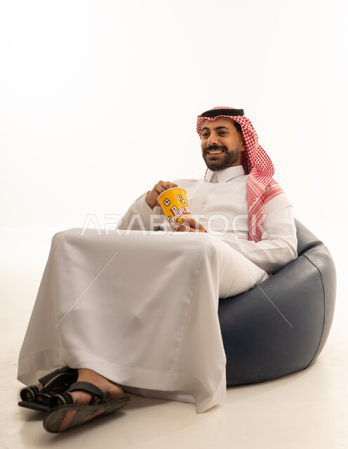 رجل سعودي بالزي التقليدي يأكل الفشار