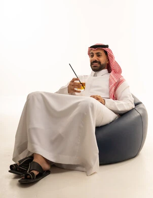 Saudi Man in Traditional Thobe Sitting with Cold Drink