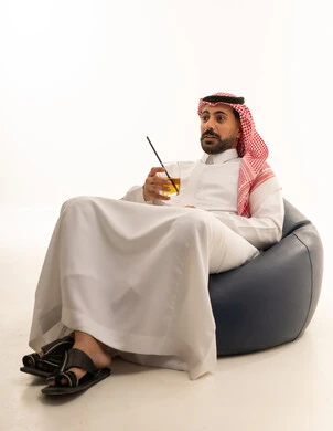Saudi Man in Thobe Sitting on Bean Bag with Juice
