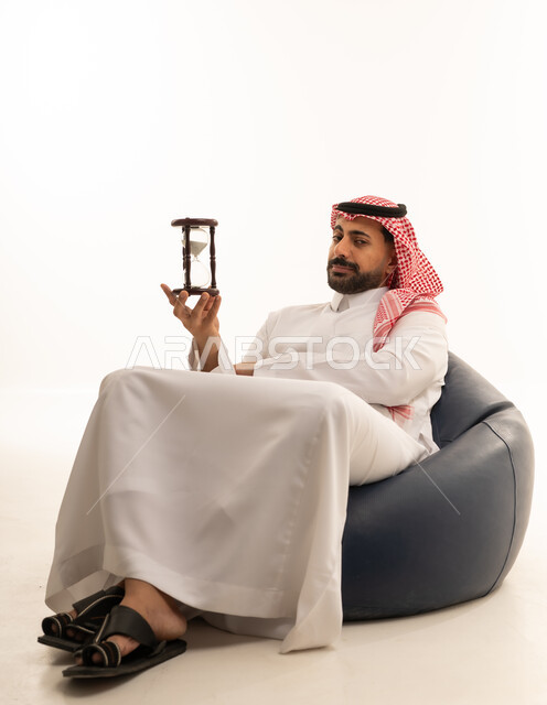 رجل سعودي مع ساعة رملية بخلفية بيضاء