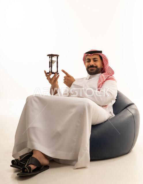 رجل سعودي مع ساعة رملية لإدارة الوقت