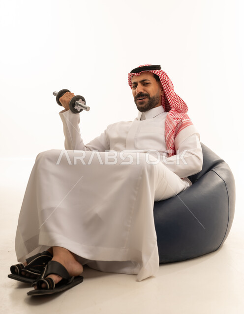 رجل سعودي بالزي التقليدي يمارس رياضة رفع الأثقال