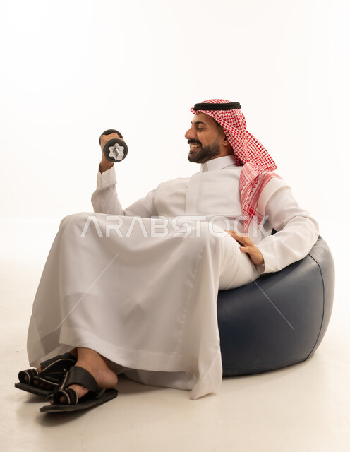 Saudi Man in Thobe Lifting Dumbbell on Bean Bag