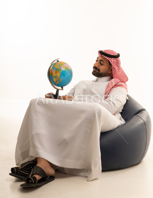 Saudi Man in Traditional Thobe Holding a Globe