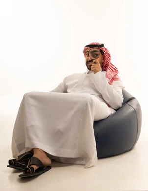 رجل سعودي مع عدسة مكبرة على مقعد محشو