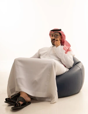 رجل سعودي بالثوب يستخدم عدسة مكبرة في الداخل