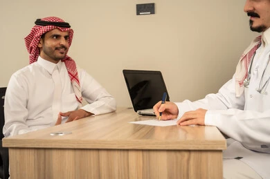 حديث جدي بين الاطباء لمتابعة احوال المريض , استخدام الحاسوب المحمول، طبيب عربي سعودي خليجي يرتدي المعطف الابيض الطبي يتحدث مع الاطباء المقيمة لتقييم الحالة الصحية ومناقشة التقارير الطبية,مفهوم الجدية في العمل