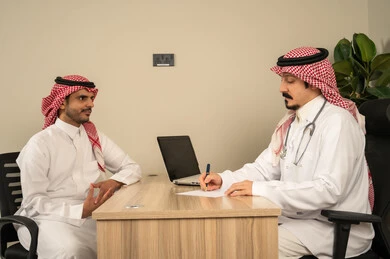 حديث جدي بين الاطباء لمتابعة احوال المريض , استخدام الحاسوب المحمول، طبيب عربي سعودي خليجي يرتدي المعطف الابيض الطبي يتحدث مع الاطباء المقيمة لتقييم الحالة الصحية ومناقشة التقارير الطبية,مفهوم الجدية في العمل