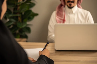 Task management and division, using a laptop, two Arab Gulf Saudi employees conducting a business meeting inside the conference room at the company headquarters, integrating modern technology with office work, studying work papers, developing projects and investments. Task management and division, using a laptop, two Arab Gulf Saudi employees conducting a business meeting inside the conference room at the company headquarters, integrating modern technology with office work, studying work papers, developing projects and investments.
