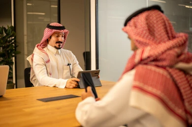 Integrating work with advanced technology, Arab Gulf Saudi employees using modern technical devices, accomplishing work tasks, Saudi professions and jobs, achieving company goals, the Saudi work environment.