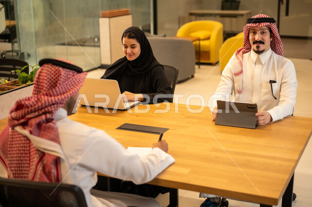 موظفين عربيين خليجيين سعوديين يستخدمون الاجهزة التقنية الحديثة، إنجاز مهام العمل ،مهن ووظائف سعودية، تحقيق أهداف الشركة، دمج العمل مع التكنولوجيا المتطورة، بيئة العمل السعودي.