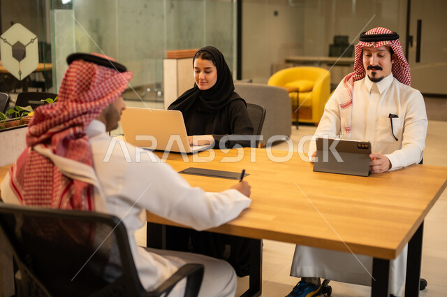 Integrating work with advanced technology, Arab Gulf Saudi employees using modern technical devices, accomplishing work tasks, Saudi professions and jobs, achieving company goals, the Saudi work environment.