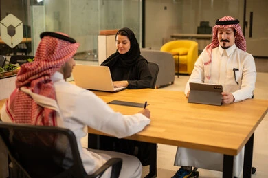 Integrating work with advanced technology, Arab Gulf Saudi employees using modern technical devices, accomplishing work tasks, Saudi professions and jobs, achieving company goals, the Saudi work environment.