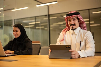 موظفين عربيين خليجيين سعوديين يستخدمون الاجهزة التقنية الحديثة، إنجاز مهام العمل ،مهن ووظائف سعودية، تحقيق أهداف الشركة، دمج العمل مع التكنولوجيا المتطورة، بيئة العمل السعودي.