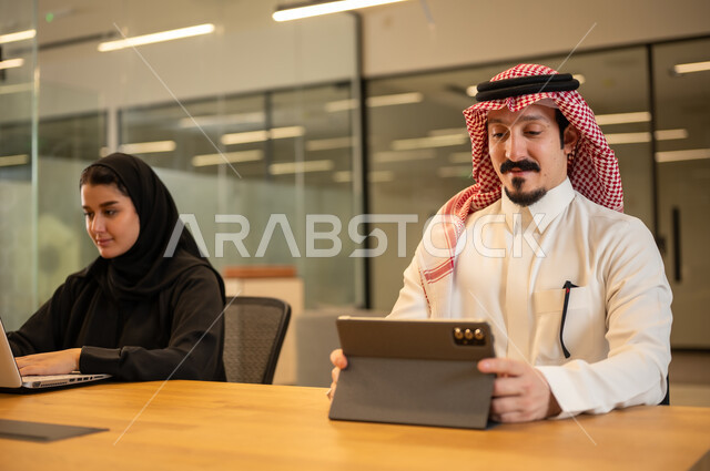 دمج العمل مع التكنولوجيا المتطورة، موظفين عربيين خليجيين سعوديين يستخدمون الاجهزة التقنية الحديثة، إنجاز مهام العمل ،مهن ووظائف سعودية، تحقيق أهداف الشركة، بيئة العمل السعودي.