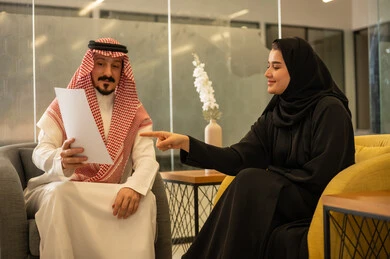 مفهوم الإدارة المتعاونة لتحقيق أهداف الشركة، موظفين عربيين خليجيين سعوديين يتناقشان في أمور العمل باستخدام الأوراق، الإشارة الى العقود و الاشراف على التطور المهني، التعاون والتفاعل الجماعي و حل المشكلات