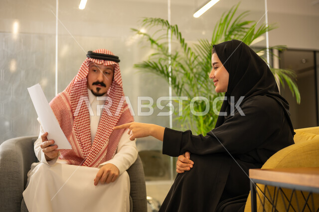 التعاون فى حل المشكلات ، مفهوم الإدارة المتعاونة لتحقيق أهداف الشركة، موظفين عربيين خليجيين سعوديين يتناقشان في أمور العمل باستخدام الأوراق، الإشارة الى العقود و الاشراف على التطور المهني، التعاون والتفاعل الجماعي و حل المشكلات