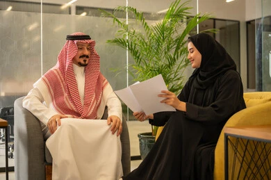 مفهوم الإدارة المتعاونة لتحقيق أهداف الشركة، موظفين عربيين خليجيين سعوديين يتناقشان في أمور العمل باستخدام الأوراق، الإشارة الى العقود و الاشراف على التطور المهني، التعاون والتفاعل الجماعي و حل المشكلات