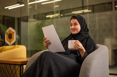 التدقيق في قراءة الملاحظات، اعداد التقارير الخاصة بالعمل، امرأة عربية سعودية خليجية محجبة ترتدي العباءة السوداء تحمل بيدها مجموعة من الاوراق البيضاء، مراجعة ومتابعة الخطط والمشاريع المكتبية بإيماءات التركيز