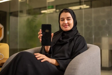 عرض شاشة سوداء فارغة, امرأة عربية سعودية خليجية محجبة ترتدي العباءة السوداء تقوم بإجراء مكالمة هاتفية عبر الهاتف المحمول, العمل في المجال المكتبي, متابعه الأعمال الادارية