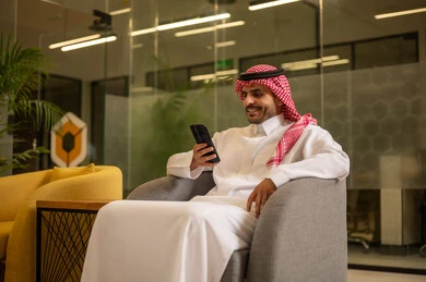 إيماءات الجودة والرضا والقبول, رجل عربي خليجي سعودي مبتسم يرتدي الثوب التقليدي والشماغ يقوم بإجراء مكالمة هاتفية عبر الهاتف المحمول, العمل في المجال المكتبي, متابعه الأعمال الادارية