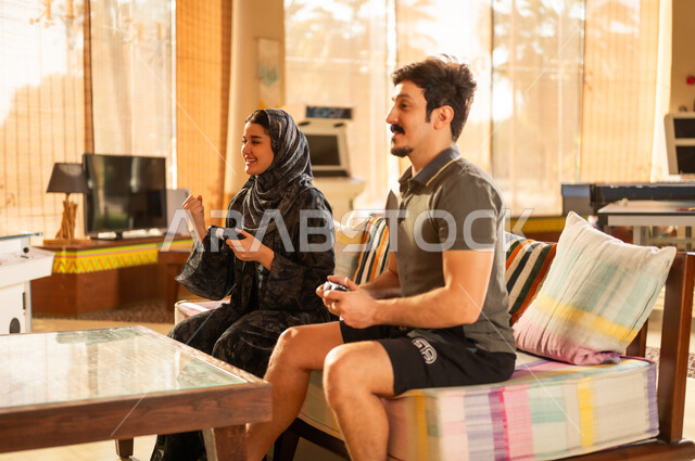 زوجان سعوديان يلعبان ألعاب الفيديو في غرفة المعيشة