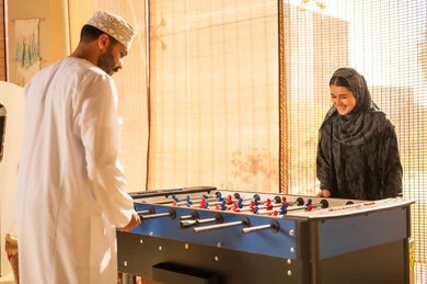 Omani Man and Woman Playing Foosball Indoors