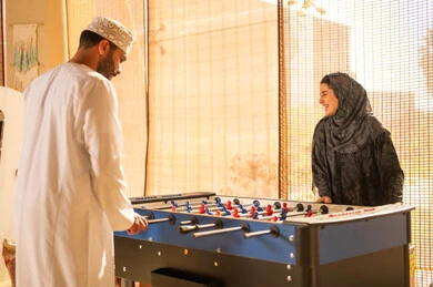 رجل وامرأة عُمانيان يلعبان كرة الطاولة الفرفيرة في الداخل