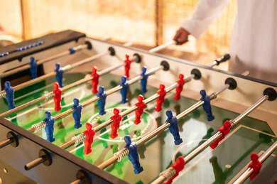 Saudi Man in Traditional Thobe Playing Foosball