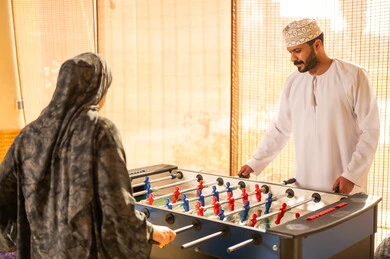 رجل وامرأة من عمان يلعبان فريرة كرة الطاولة