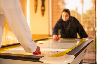 Arab Man and Woman Playing Air Hockey Indoor