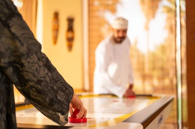 Omani Man Playing Air Hockey in Warm Indoor Setting