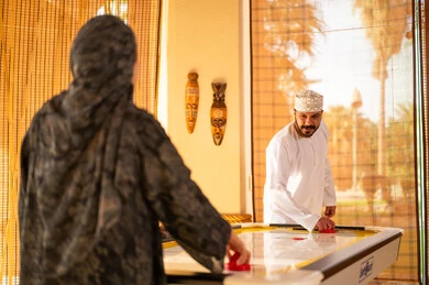 Omani Man Playing Air Hockey in Traditional Dress