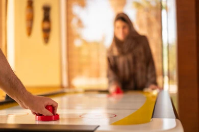 Saudi Woman Playing Air Hockey in Gaming Area