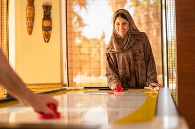 Saudi Woman Playing Air Hockey in Traditional Dress