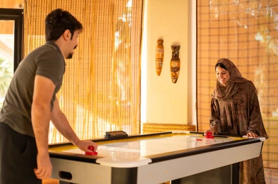 Saudi Couple Playing Air Hockey in Indoor Game Room