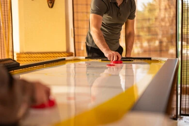 Men Playing Air Hockey Game in Indoor Recreation Room