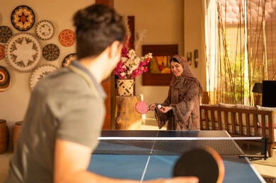 امرأة عربية تلعب تنس الطاولة بالعباءة التقليدية