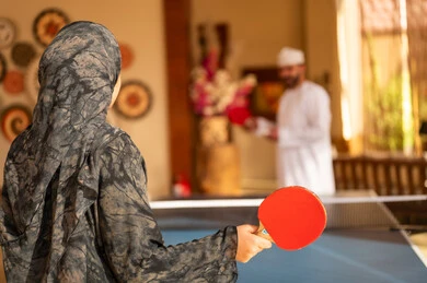 زوجان عمانيان يلعبان تنس الطاولة بالزي التقليدي
