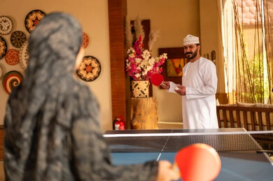 رجل وامرأة من عمان يلعبان تنس الطاولة في الداخل