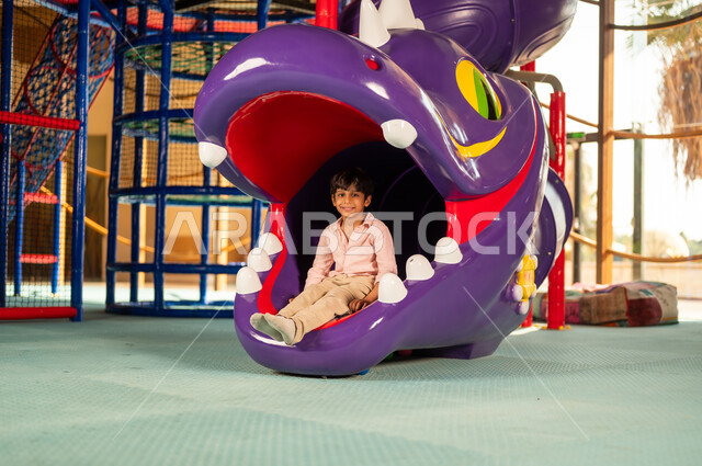 Saudi Boy Playing in Dragon Slide at Indoor Playground