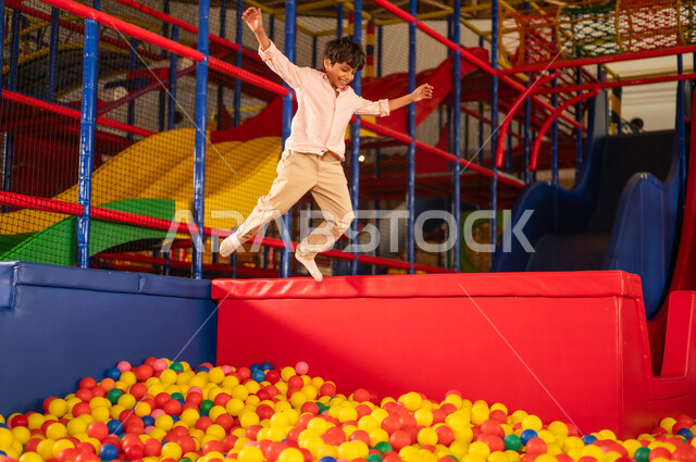 Arab Boy Jumping into Indoor Playground Ball Pit